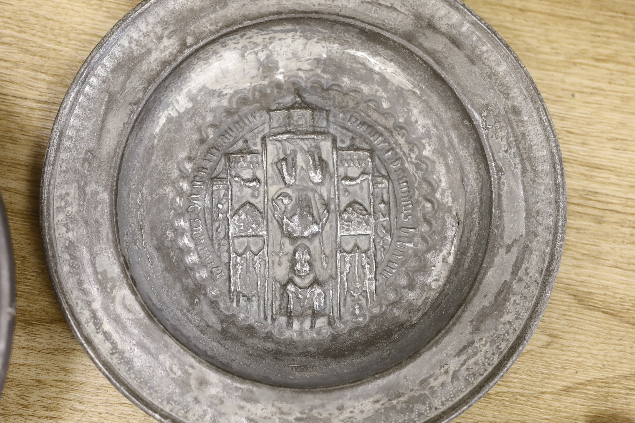 An 18th century pewter dish, an embossed pewter plate and a pair of iron fire tongs